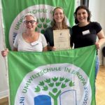 Drei Frauen halten einen grünen Banner mit Umweltschule in Europa