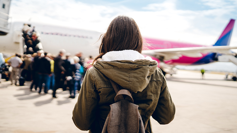 Frau auf Flugfeld beim Einstieg in ein Flugzeug