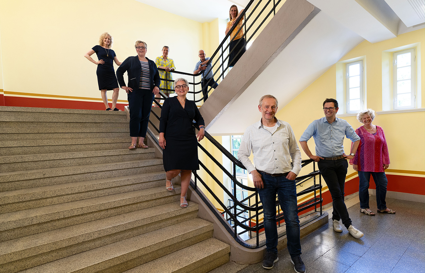 Personen stehen auf einer Treppe und schauen in die Kamera
